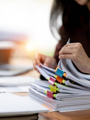 Businesswoman hands working in Stacks of paper files for searching and checking unfinished document achieves on folders papers